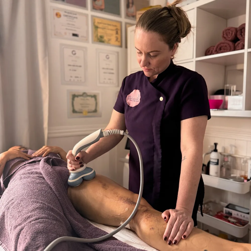 Andrea, in her plum uniform, treating a client with an aesthetic technology device at the Belíssima studio