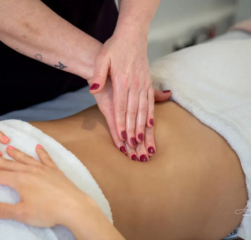 Close-up of expert hands performing manual lymphatic drainage on a client's abdomen